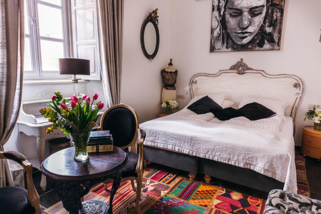 a bedroom with a bed and a table with a vase of flowers at Prijeko Palace in Dubrovnik