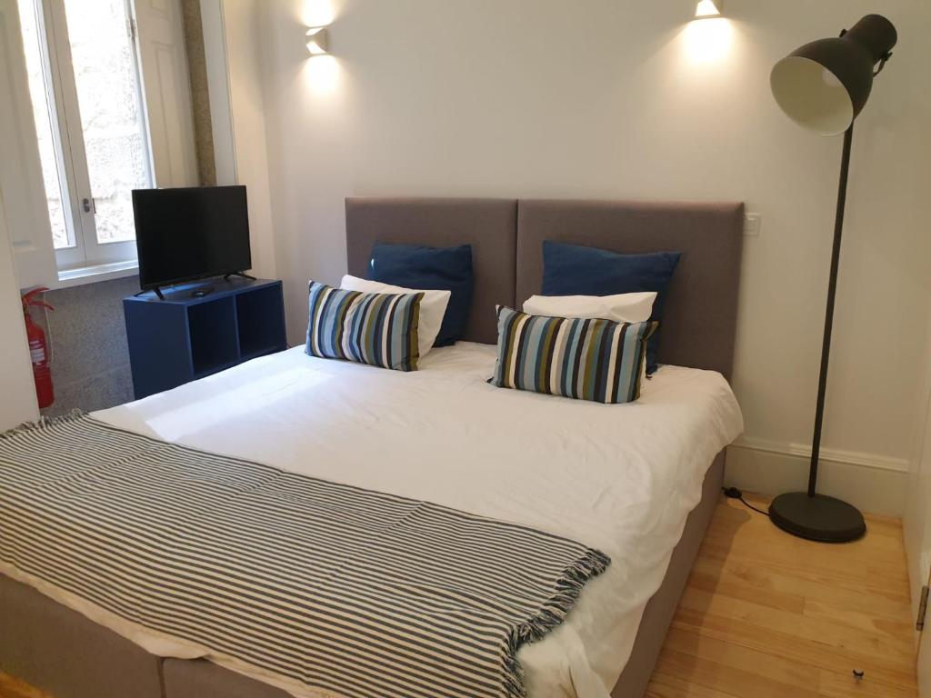 Cette chambre comprend un lit avec deux oreillers et une télévision. dans l'établissement Citybreak-Apartments Caldeireiros, à Porto