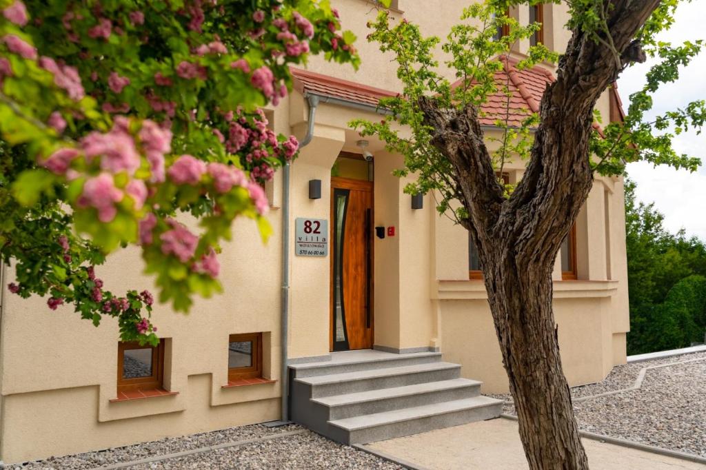 un bâtiment avec des escaliers et un arbre avec des fleurs roses dans l'établissement Apartamenty, Boutique Rooms Villa 82, Parking, à Gorzów Wielkopolski