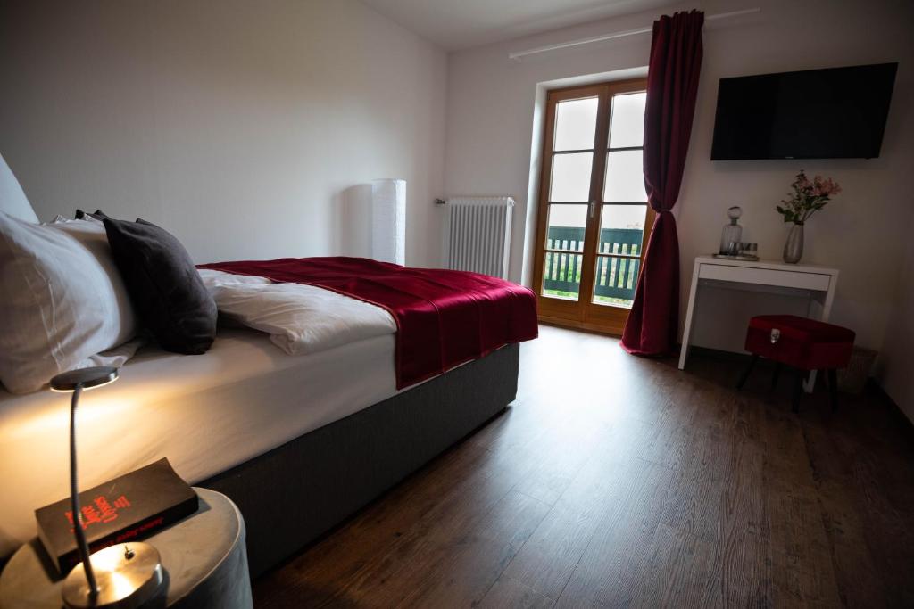 a bedroom with a bed with a red blanket and a window at Landgasthof Hittenkirchen in Bernau am Chiemsee