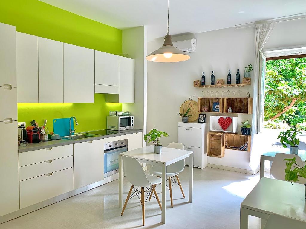una cocina con armarios blancos y una pared verde en Casa Italia, en Verona