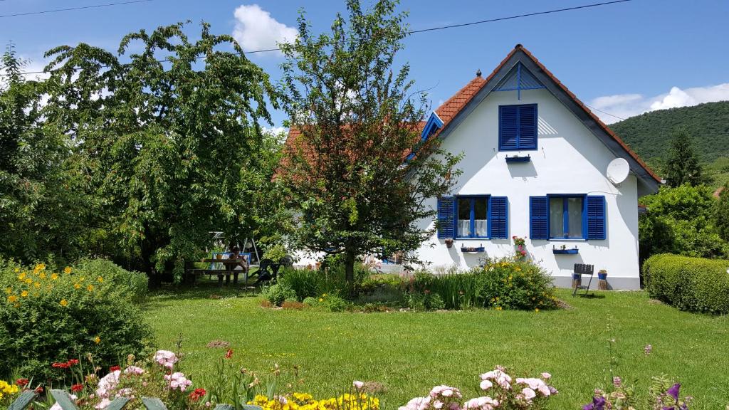 a white house with blue shutters on a yard at Áron Apartman in Badacsonytomaj