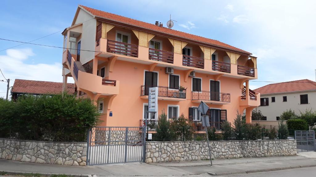 Un edificio naranja con balcones y una valla en Pansion Maria, en Zadar