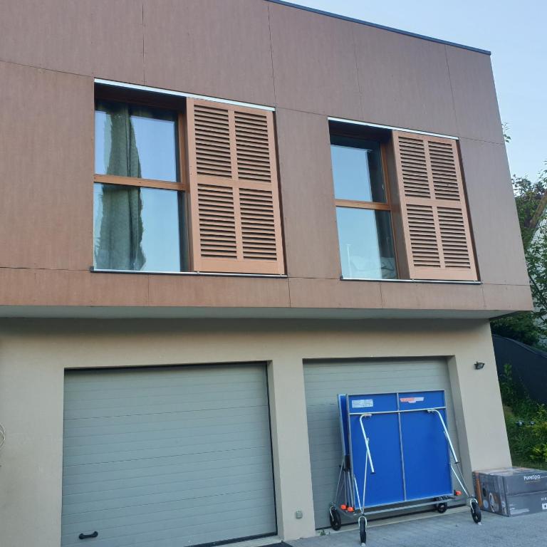 une maison avec deux portes de garage et une porte bleue dans l'établissement Royal - Liza's house, à Saint-Germain-en-Laye
