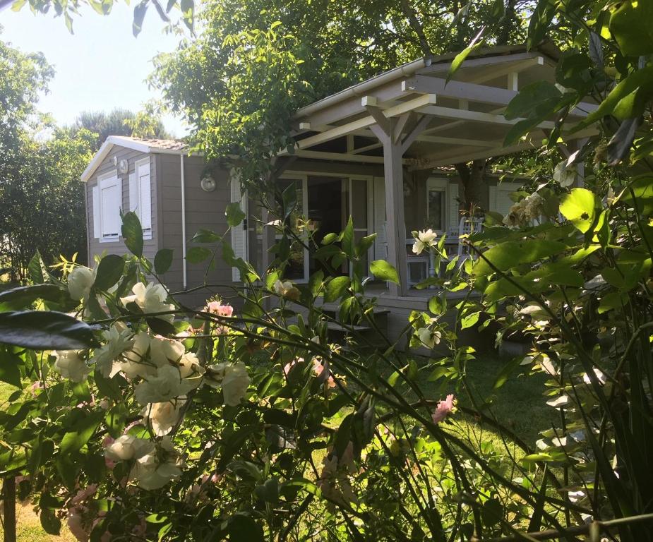 a house in the trees with flowers in the foreground at Au Temps Suspendu - 3 chambres - Au coeur de la nature - À 10 minutes des commerces in Vielle-Tursan