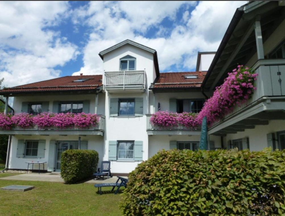 a large white building with pink flowers on the balconies at Ferienwohnanlage Brünnstein Wohnung 54 in Oberaudorf