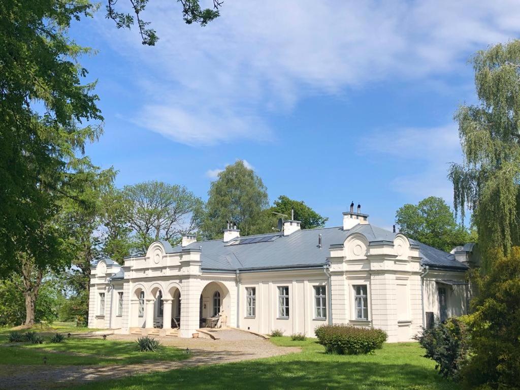 duża biała rezydencja z dachem w obiekcie Zamość Dwór Udrycze w mieście Udrycze