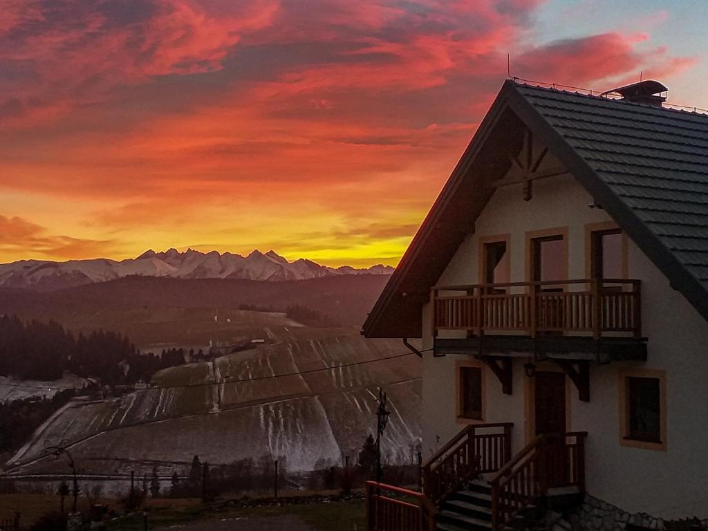 a house with a sunset in the mountains at Domek na wzgórzu in Łapsze Niżne