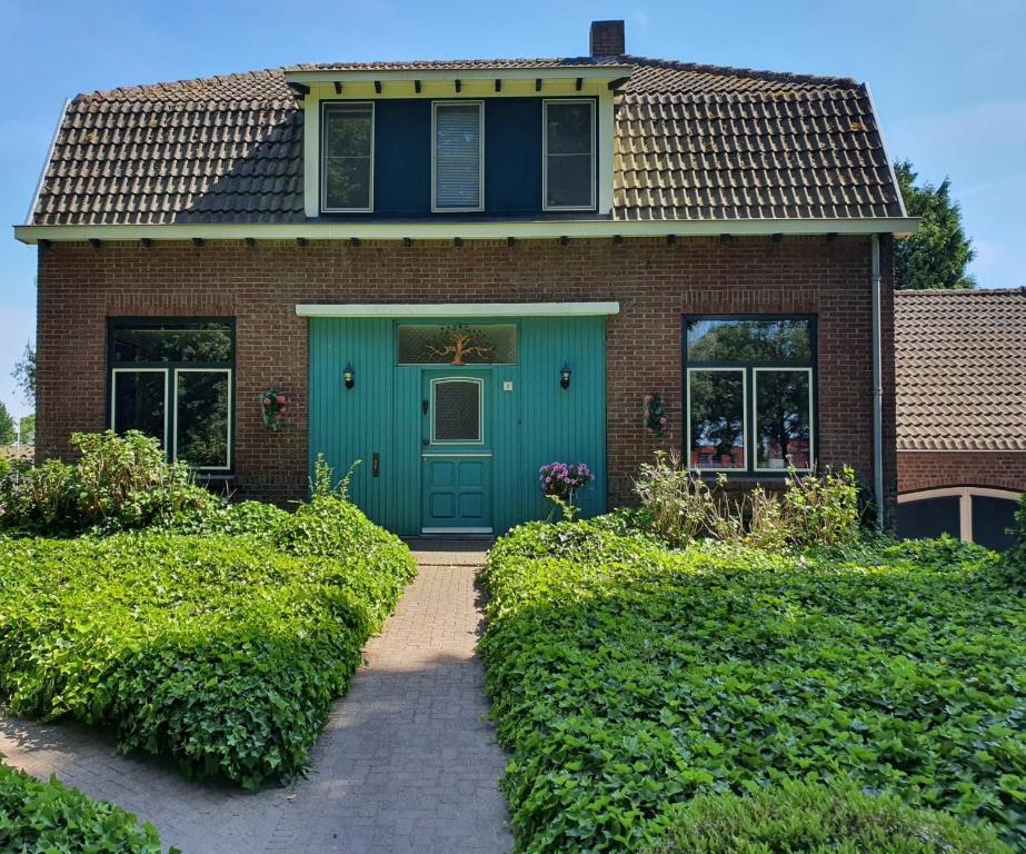 uma casa de tijolos com uma porta azul e arbustos em De Vliegende Vlinder em Nederweert