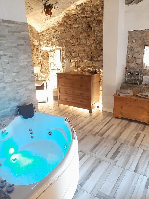 eine Badewanne in einem Zimmer mit einer Steinmauer in der Unterkunft La grotta dell'Antica Calvasino - Jacuzzi in Lezzeno