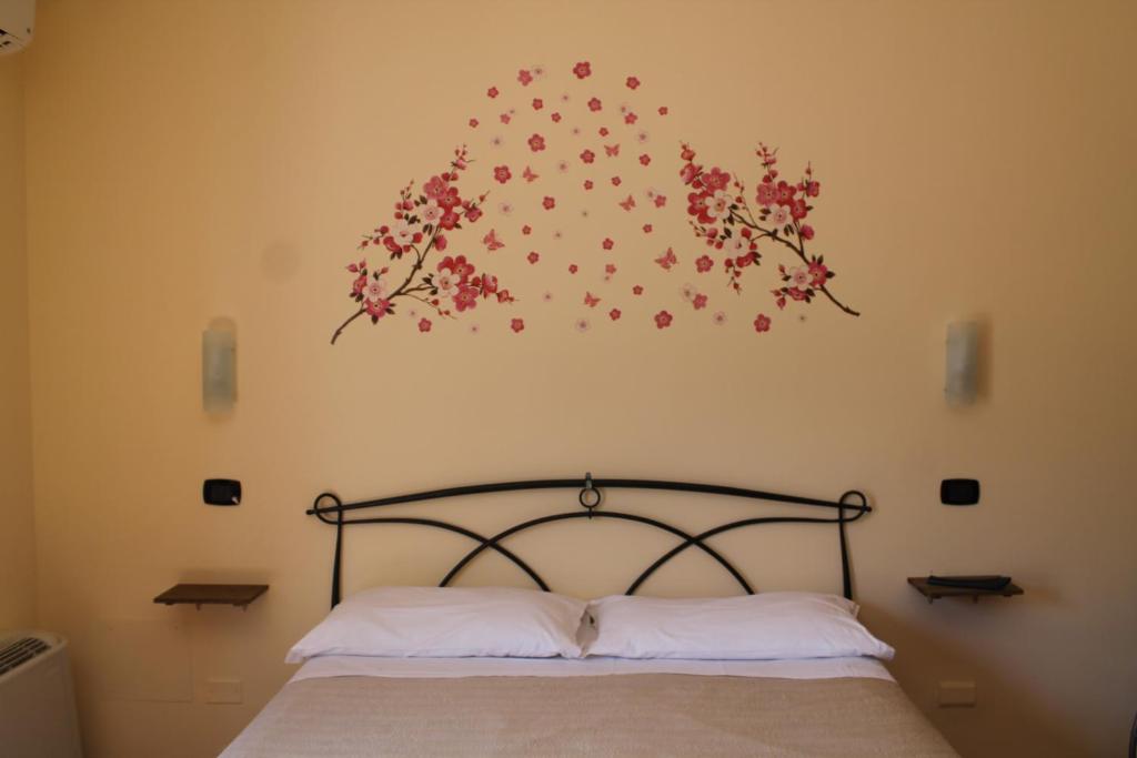 1 dormitorio con 1 cama con flores en la pared en Piccola Perla Guest House, en Valmontone