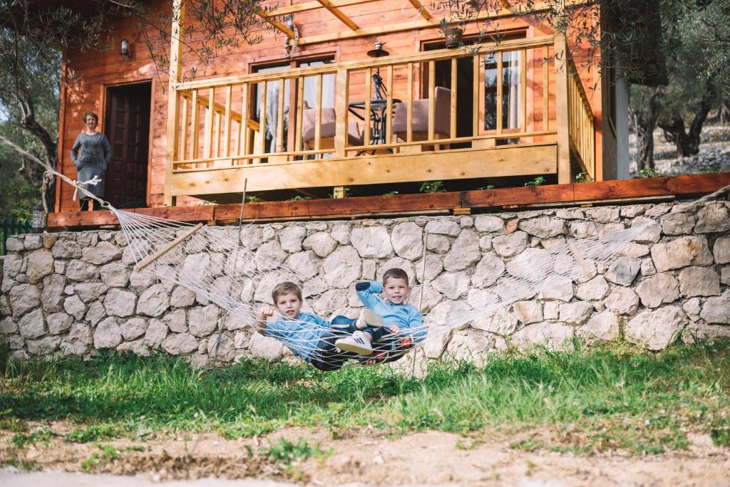 Dois rapazes deitados numa rede em frente a uma parede de pedra. em Cottage Four Olives em Ulcinj