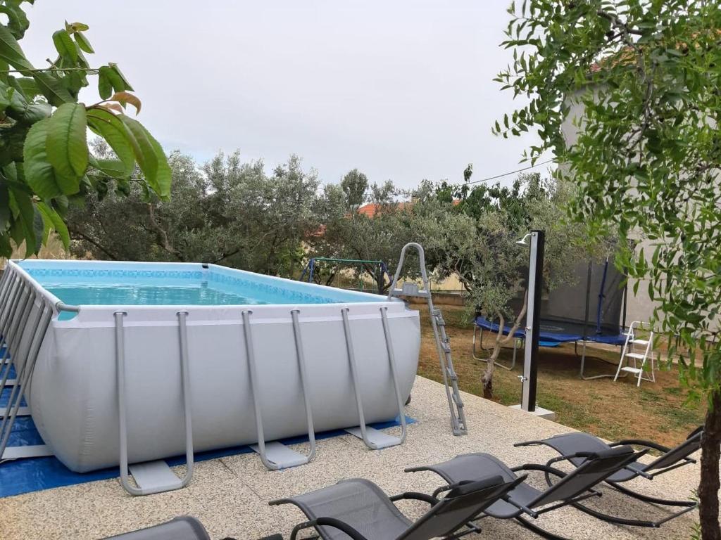 a large bath tub sitting next to chairs in a yard at Apartment Ante in Bibinje