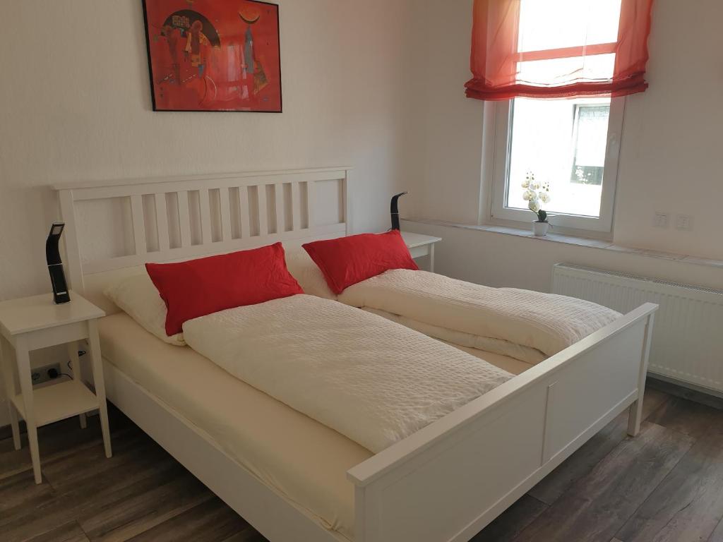 Bett mit zwei roten Kissen auf einem Zimmer in der Unterkunft Ferienwohnung Leilas Lodge in Langelsheim
