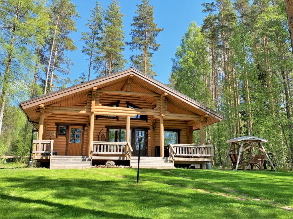 une cabane en rondins avec deux bancs dans l'herbe dans l'établissement Lappalaisen lomamökit Norpparanta, à Puumala