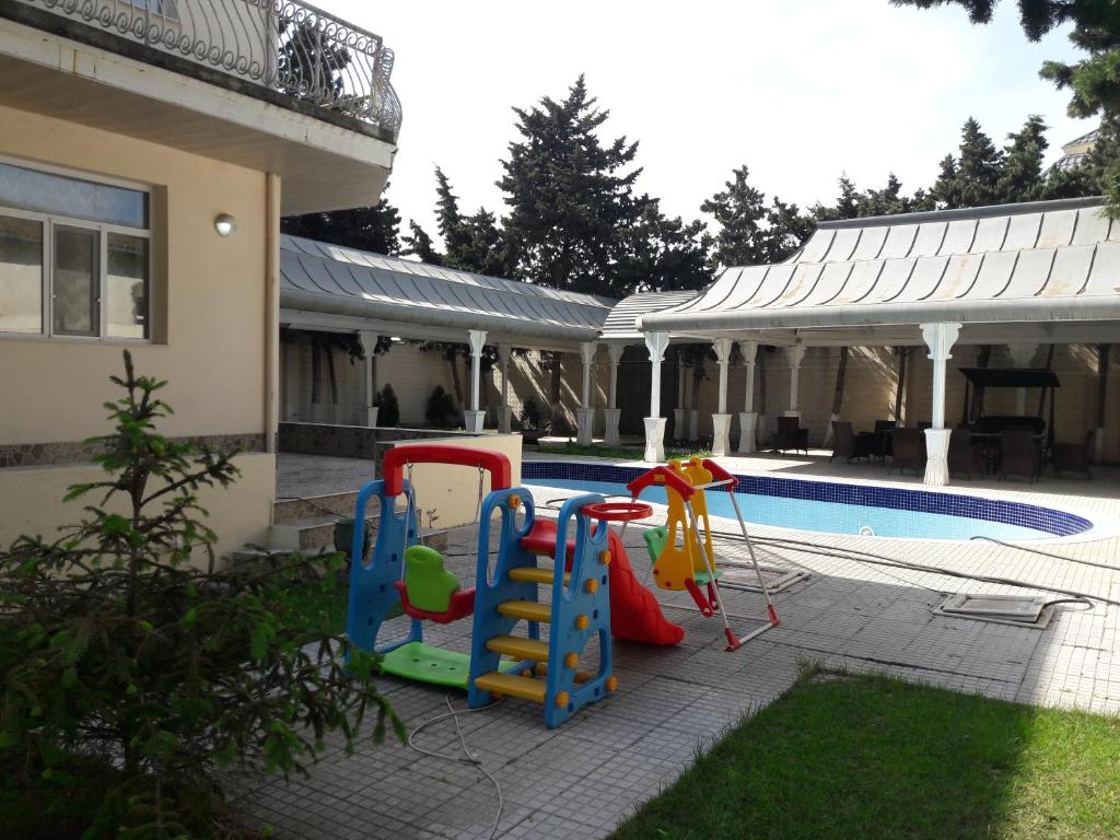 a backyard with a play set and a pool at Mardakan Cottage House in Mardakan