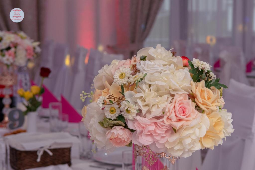 um vaso cheio de flores rosas e brancas sobre uma mesa em HOTEL CORA Bistrita em Bistriţa