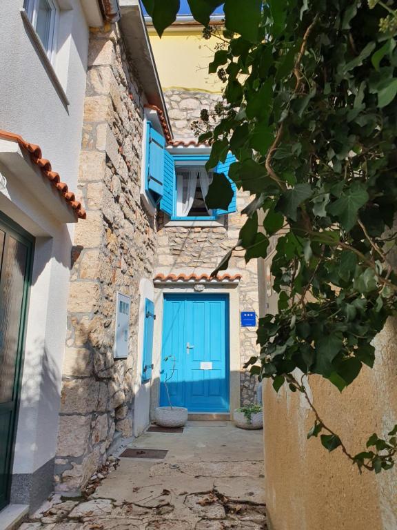 uma porta azul numa casa com uma parede de pedra em Little Summer House em Baska