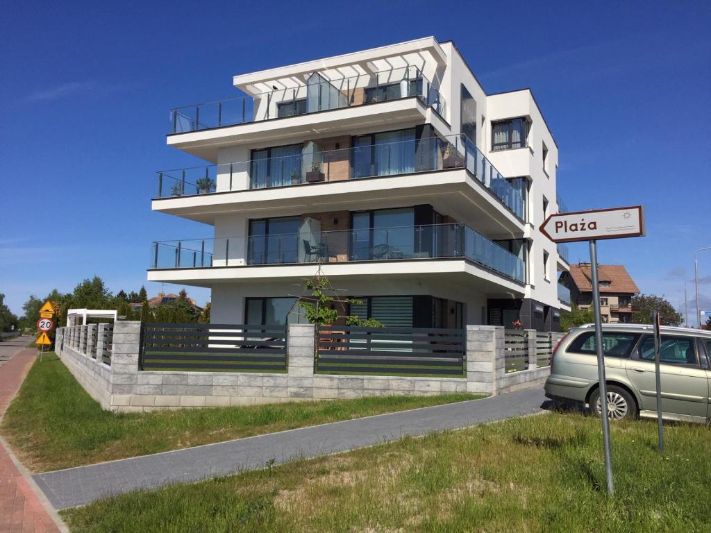 a white building with a car parked in front of it at Apartamenty Azure Premium Baltic in Kołobrzeg