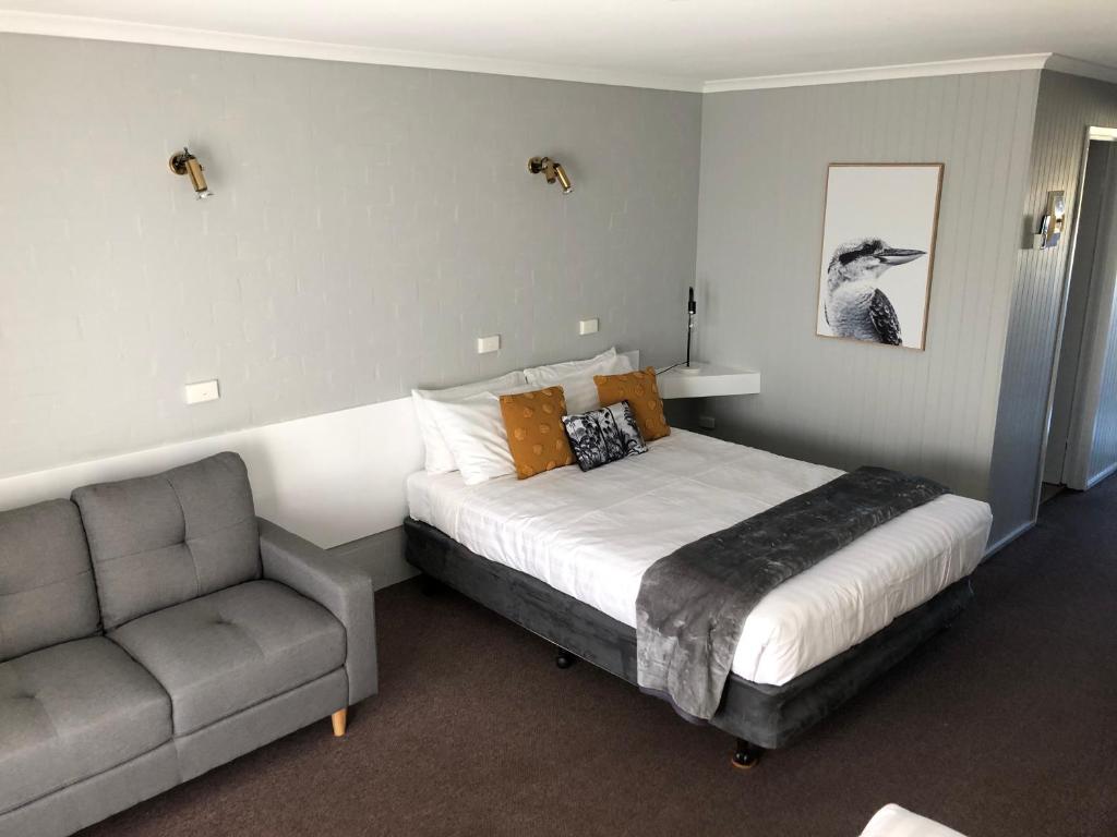 a bedroom with a bed and a chair at Country Roads Motor Inn in West Wyalong