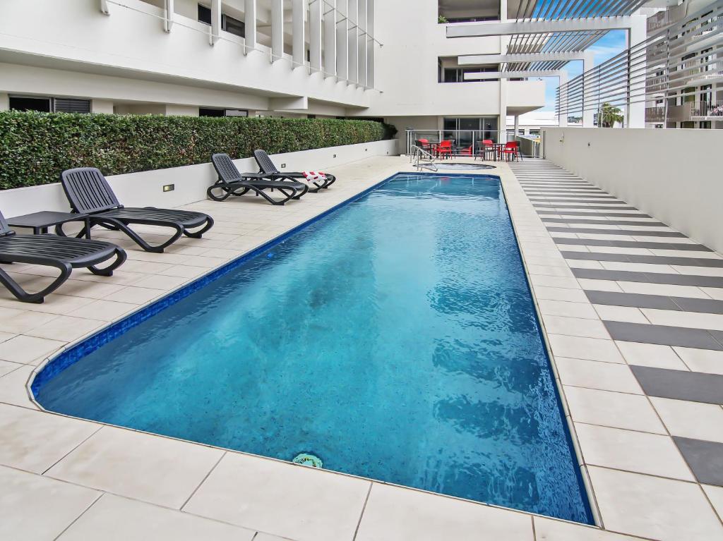 a swimming pool on a building with chairs at Space Holiday Apartments in Maroochydore