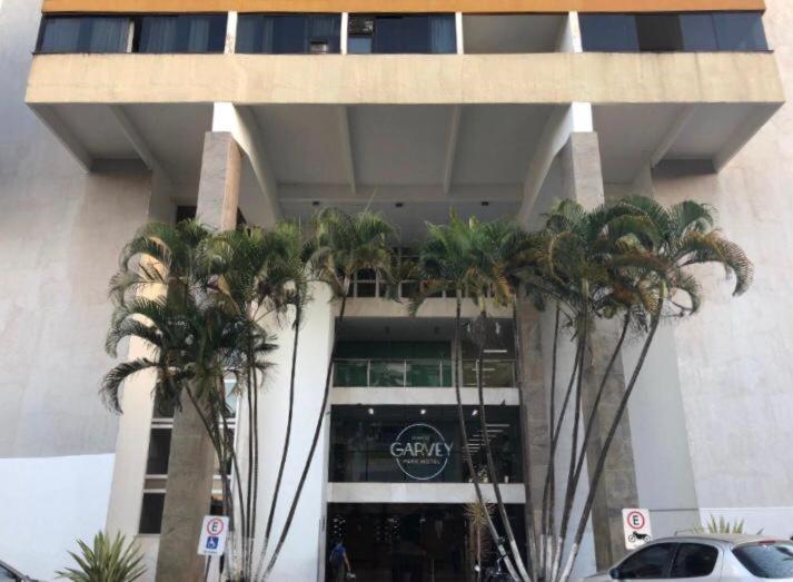 un bâtiment avec des palmiers en face de celui-ci dans l'établissement Sian Apart Hotel Garvey, à Brasilia
