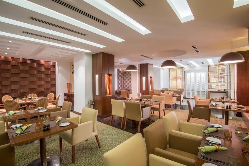 فندق كراون بلازا صحار في صحار: مطعم فيه طاولات وكراسي في الغرفة