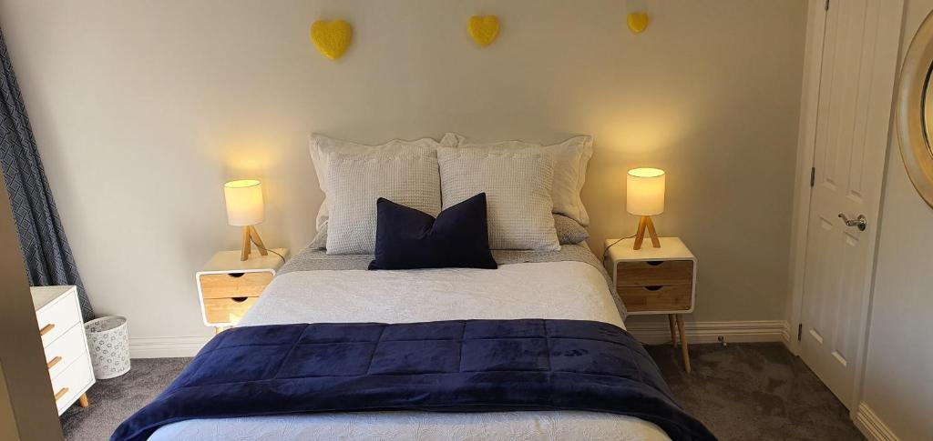 1 dormitorio con 1 cama con almohadas y 2 lámparas en Takapuna Beach Accommodation, en Auckland
