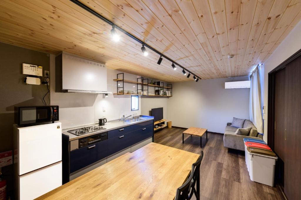 佐世保的住宿－Rakuten STAY HOUSE x WILL STYLE Sasebo 104，厨房以及带沙发和桌子的客厅。