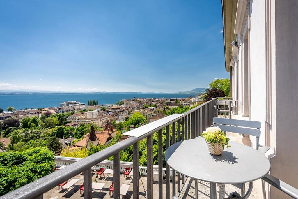 uma varanda com uma mesa e vista para o oceano em Hôtel Alpes & Lac em Neuchâtel