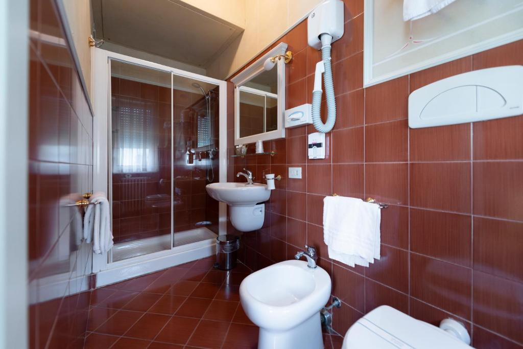 a bathroom with a toilet and a shower and a sink at Hotel Gennarino in Livorno
