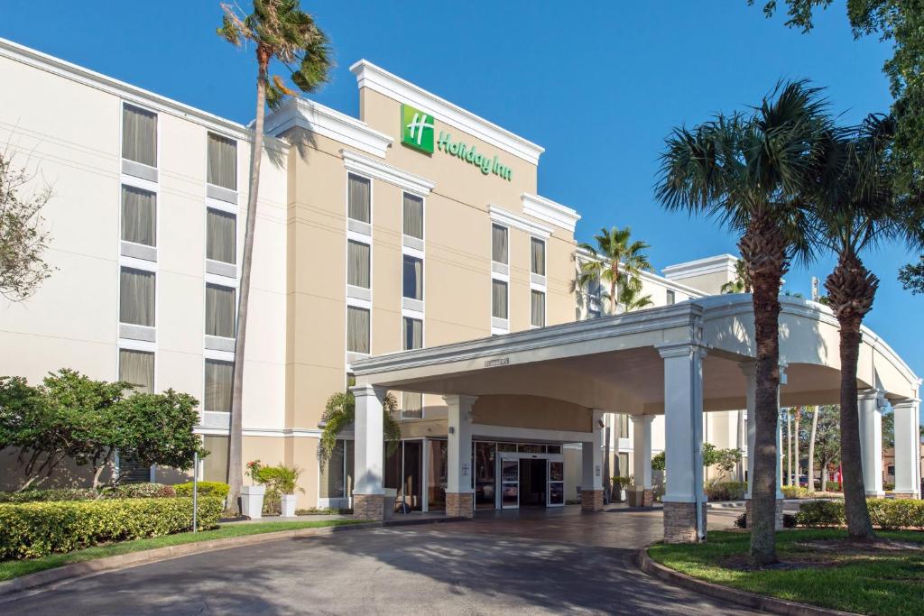 an exterior view of a hotel with palm trees at Holiday Inn Melbourne-Viera Conference Ctr, an IHG Hotel in Melbourne