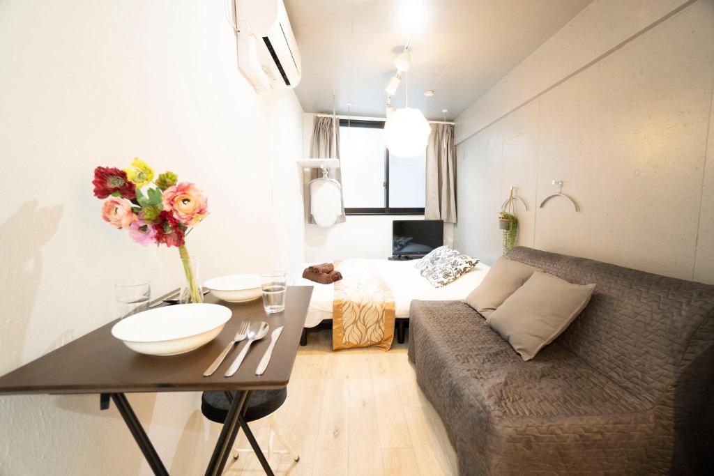 - un salon avec un canapé et une table fleurie dans l'établissement Hill Side Terrace Hiroo Shibuya 203, à Tokyo