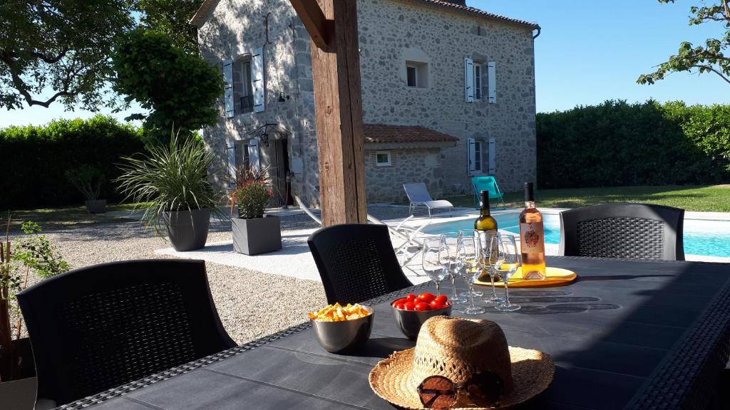 a table with a bottle of wine and a hat on it at Gîte des Magnolias in Nérac