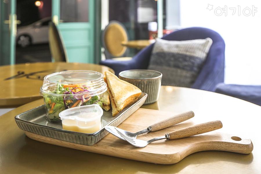 una bandeja con un sándwich y ensalada en una mesa en Yangsan Seoksan W Hotel, en Yangsan