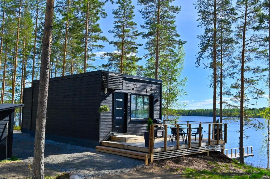 a black tiny house on the shore of a lake at TOP Star Lakeland Viitasaari in Viitasaari