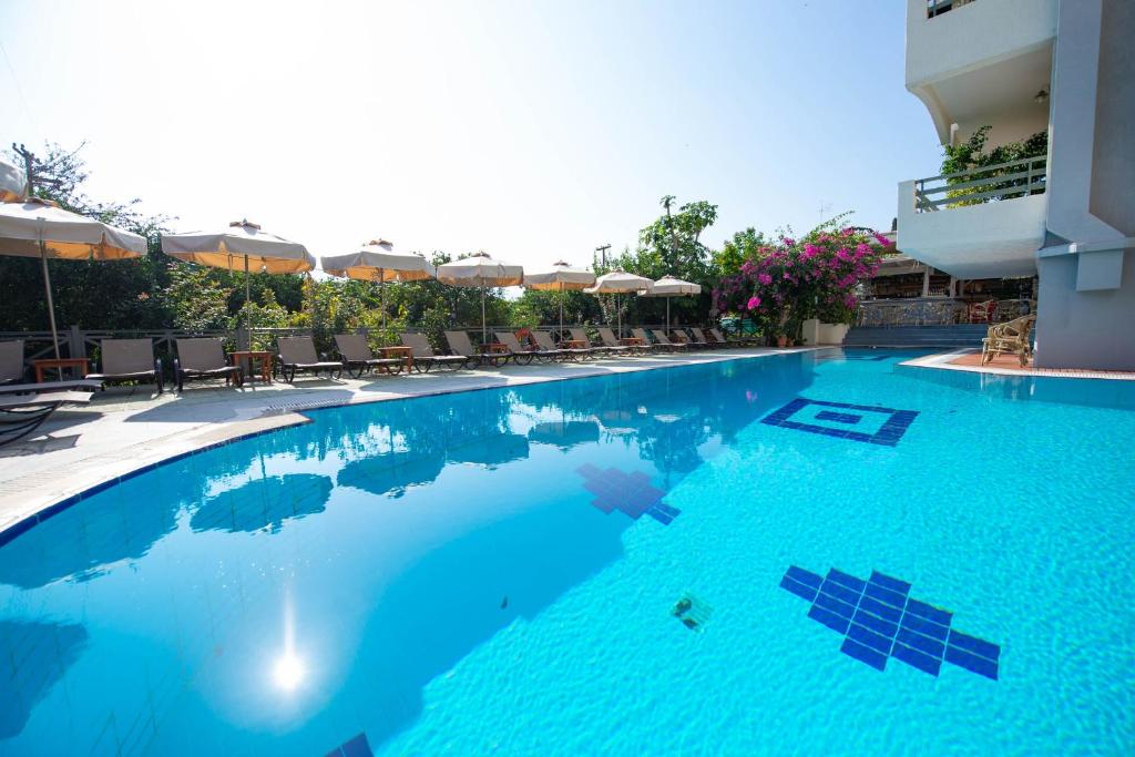 a large blue swimming pool with chairs and umbrellas at Saga Hotel in Poros