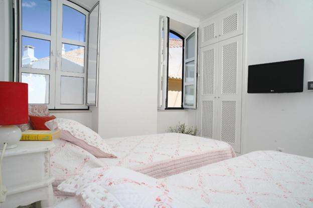 a bedroom with a bed and a tv and windows at Studio Rosmarin in Faro