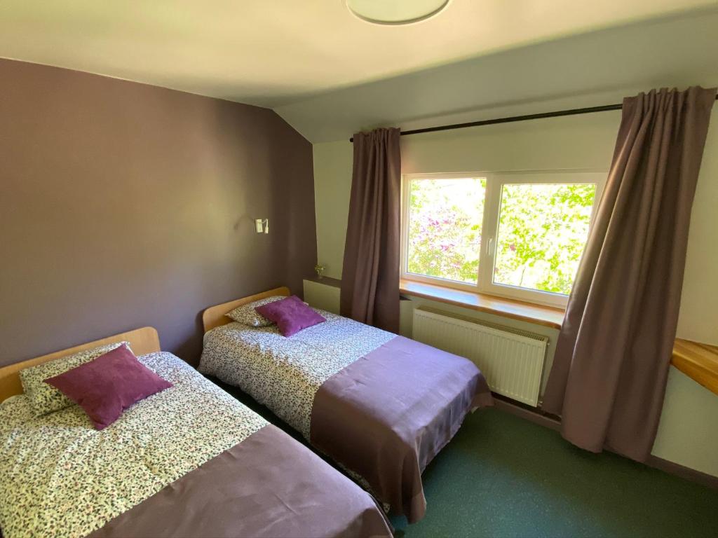 een slaapkamer met 2 bedden en een raam bij Guest House Pilsētnieki in Slampe