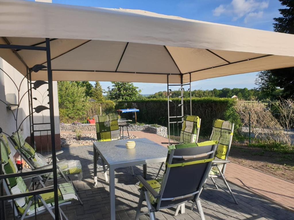 a table and chairs under an umbrella on a patio at Skibbi`s Ferienhaus an der Sonnenloipe in Friedrichsbrunn