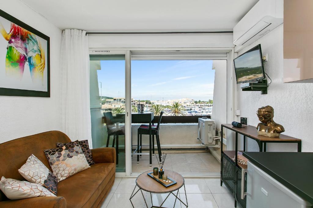 a living room with a couch and a balcony with a view at L'After Port Nature in Cap d'Agde
