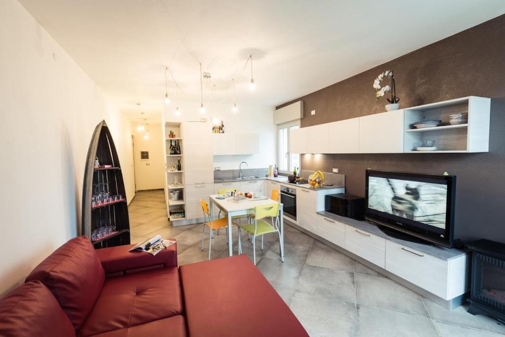 uma sala de estar com um sofá, uma televisão e uma cozinha em Cattleya em Grado