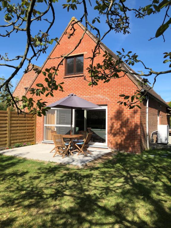 a brick house with a table and an umbrella at Alix in Zuienkerke