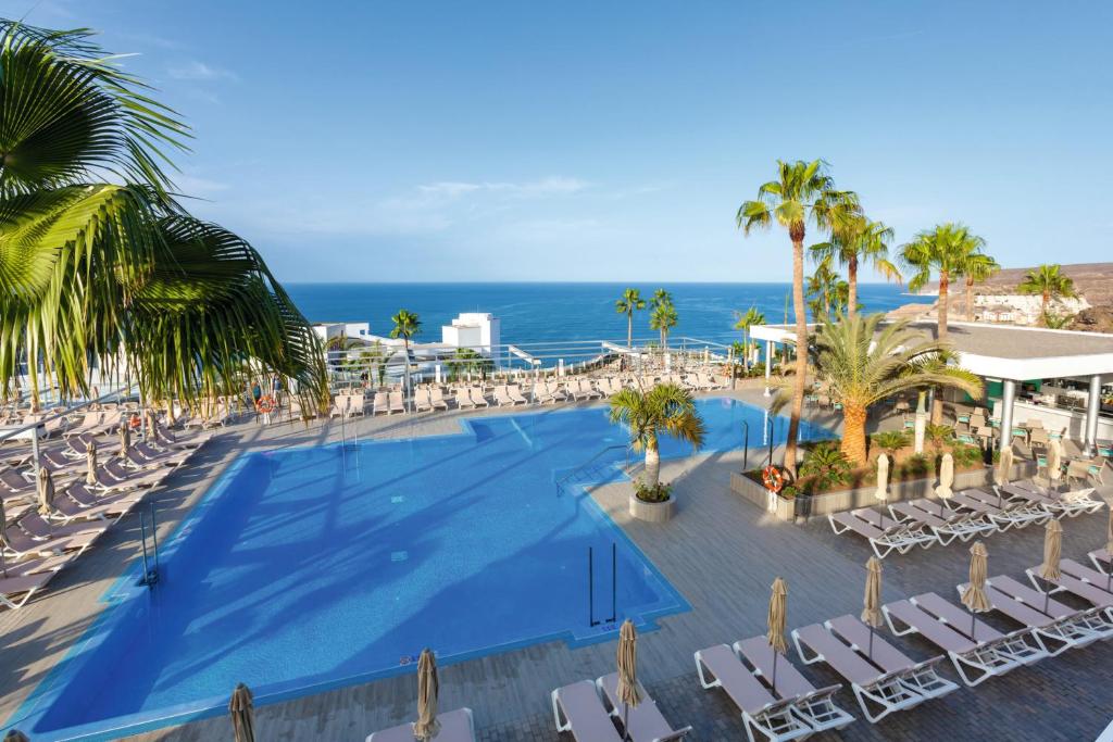 an overhead view of a pool with chairs and the ocean at Riu Vistamar Gran Canaria - All Inclusive in Puerto Rico de Gran Canaria