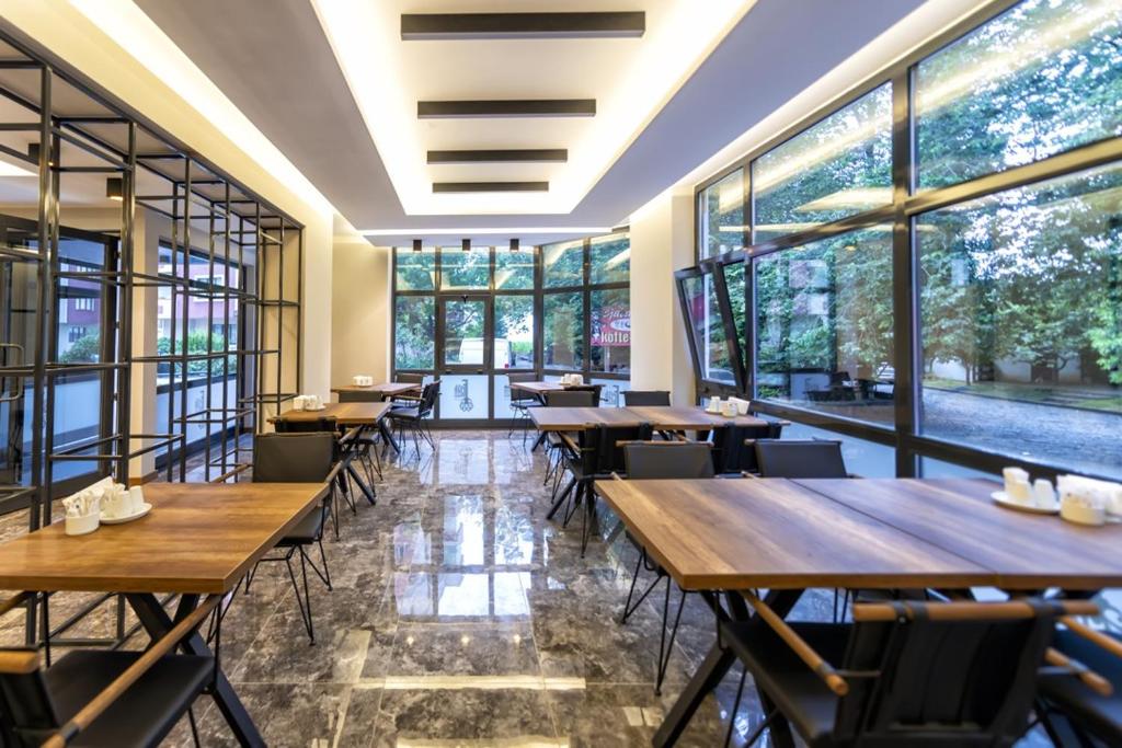 a restaurant with wooden tables and chairs and large windows at Ferah Suites Hotel in Trabzon