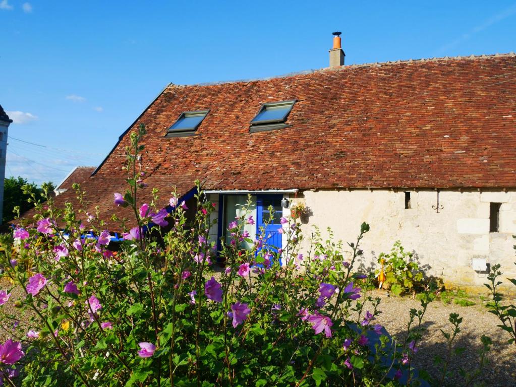 una casa de campo con flores púrpuras delante en Au Coeur de la Cour, en Saint-Georges-sur-Cher