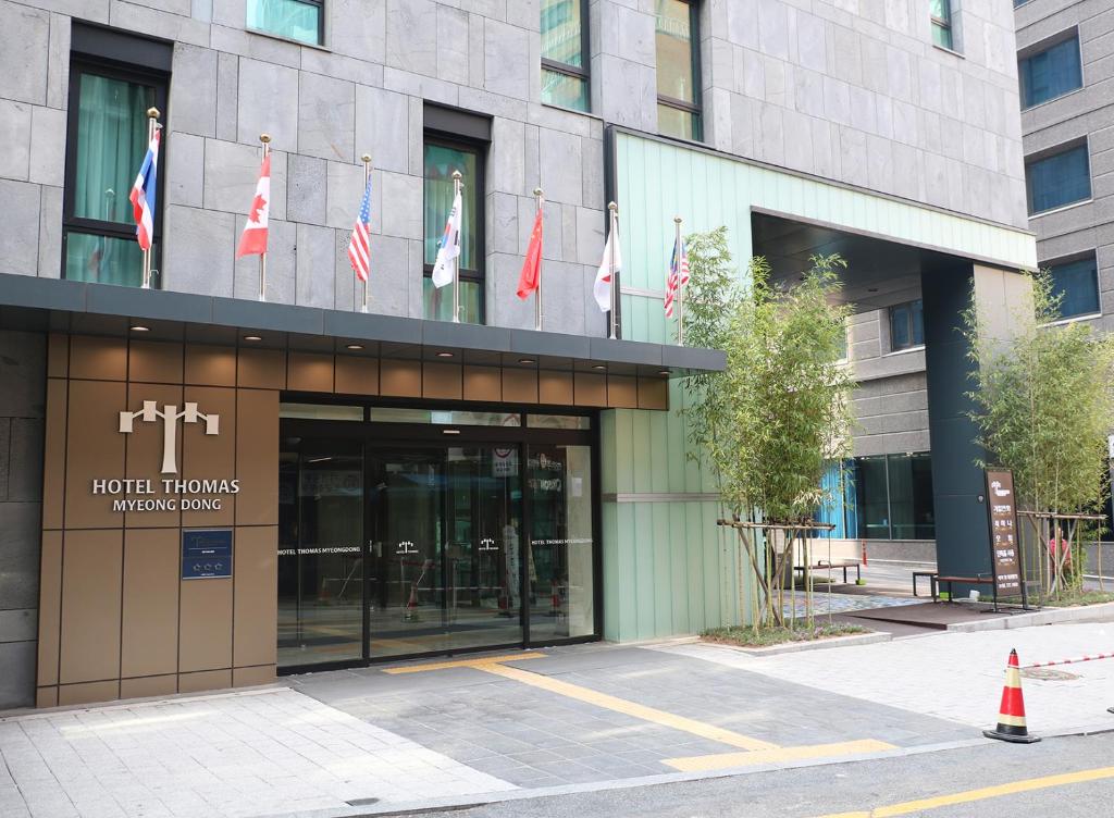 un bâtiment avec des drapeaux sur son côté dans l'établissement Hotel Thomas Myeongdong, à Séoul
