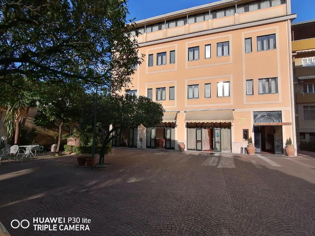 un gran edificio con un árbol delante en Hotel Giardino degli Aranci, en Frattamaggiore