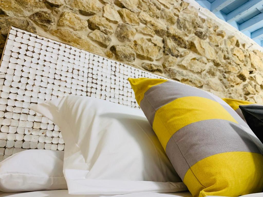 1 cama con almohadas amarillas y blancas junto a una pared de piedra en LA CASA REBONITA, en Candelario