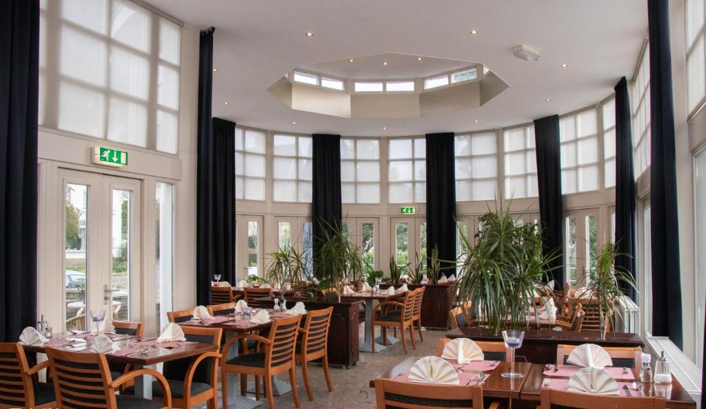 a restaurant with tables and chairs and large windows at Hotel 2000 Valkenburg in Valkenburg